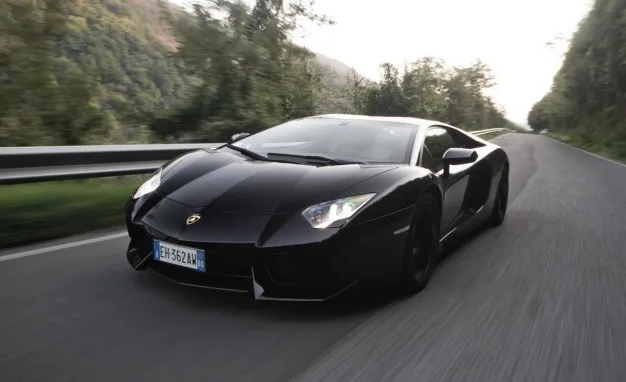 Μαύρη Lamborghini Aventador σε κίνηση σε επαρχιακό δρόμο.