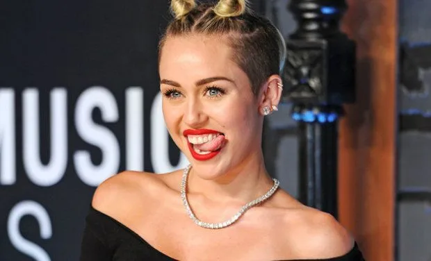 Η Miley Cyrus με χαρακτηριστικό χτένισμα και κόκκινο κραγιόν βγάζει τη γλώσσα της.
