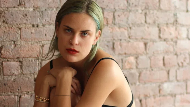 Η Tallulah Willis με πράσινα μαλλιά μπροστά από τοίχο με τούβλα.