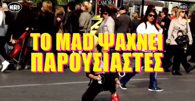 Πλήθος κόσμου σε εξωτερικό χώρο με κίτρινα γράμματα που αναφέρουν ότι το Mad ψάχνει παρουσιαστές.