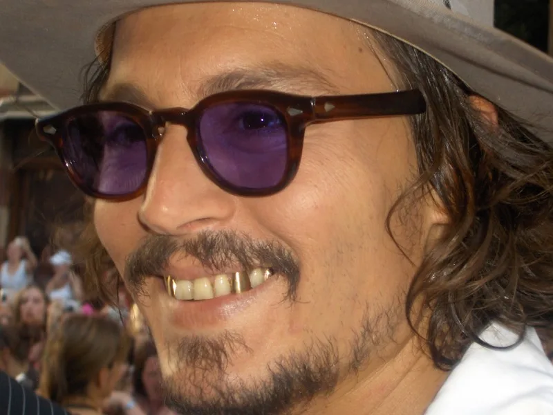 Ο Johnny Depp με καπέλο, γυαλιά με μωβ φακούς και χρυσά δόντια.