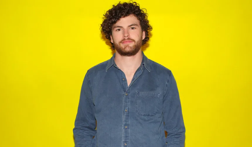 Ο Vance Joy με μπλε πουκάμισο σε κίτρινο φόντο