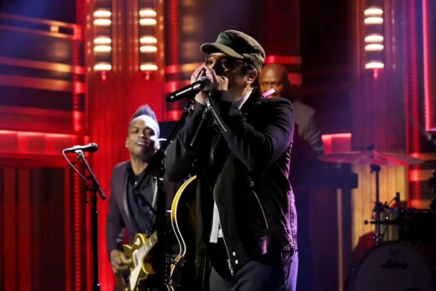 Ο Jimmy Fallon στη σκηνή υποδυόμενος τον Bono, κρατώντας μικρόφωνο και φυσαρμόνικα.