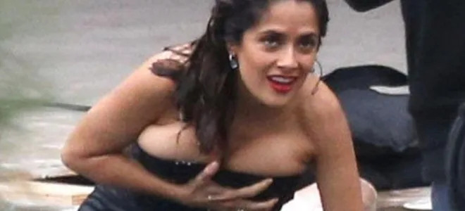 Η Salma Hayek με βρεγμένο μαύρο φόρεμα προσπαθεί να το κρατήσει στη θέση του.