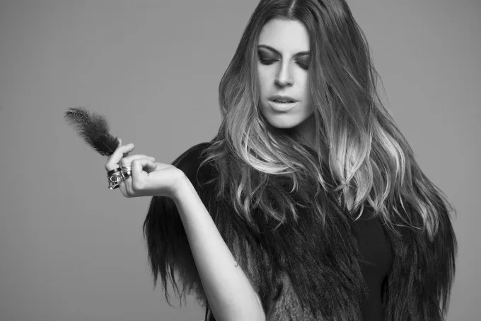 Η Angelika Dusk σε ασπρόμαυρο πορτρέτο κρατώντας ένα φτερό.