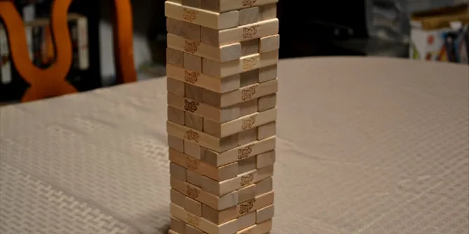 Ένας ψηλός πύργος από ξύλινα τουβλάκια Jenga πάνω σε τραπέζι.