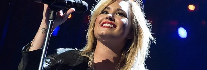 Η Demi Lovato τραγουδάει στη σκηνή κρατώντας μικρόφωνο.