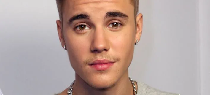 Κοντινό πορτρέτο του Justin Bieber με σκουλαρίκια και αλυσίδα.