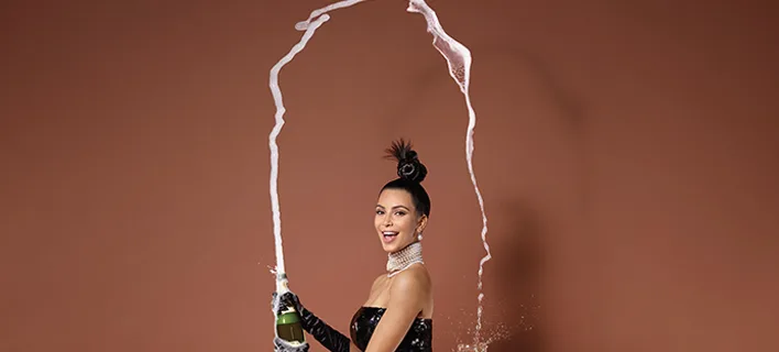 Η Kim Kardashian ποζάρει ανοίγοντας μια σαμπάνια.