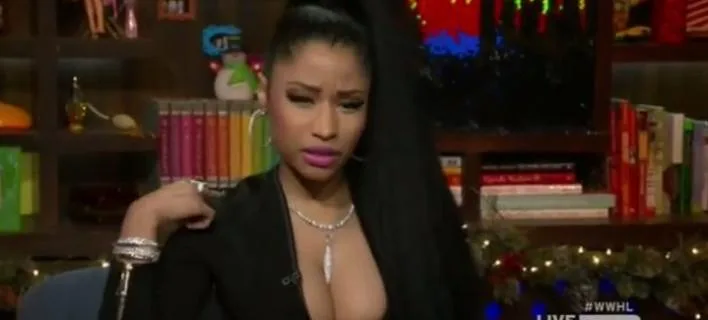 Η Nicki Minaj σε τηλεοπτική εκπομπή με μαύρο ρούχο και εντυπωσιακά κοσμήματα.