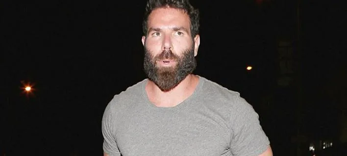 Ο Dan Bilzerian με γκρι μπλουζάκι και πυκνή γενειάδα σε νυχτερινό φόντο.