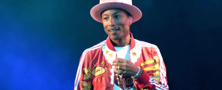 Ο Pharrell Williams στη σκηνή με καπέλο και κόκκινο τζάκετ