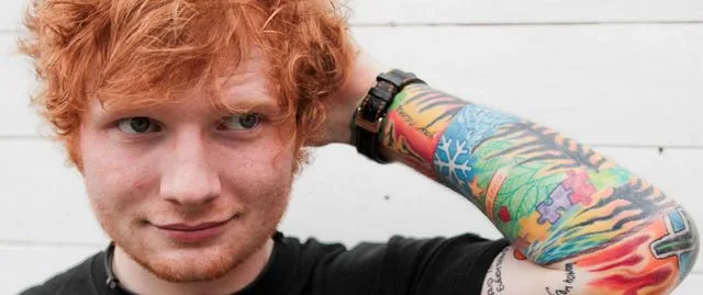 Ο Ed Sheeran με κόκκινα μαλλιά και πολύχρωμα τατουάζ στο χέρι.