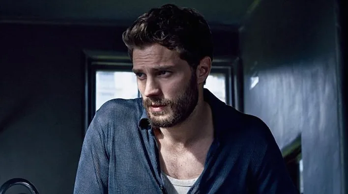 Ο Jamie Dornan με σκούρο πουκάμισο και μούσι.