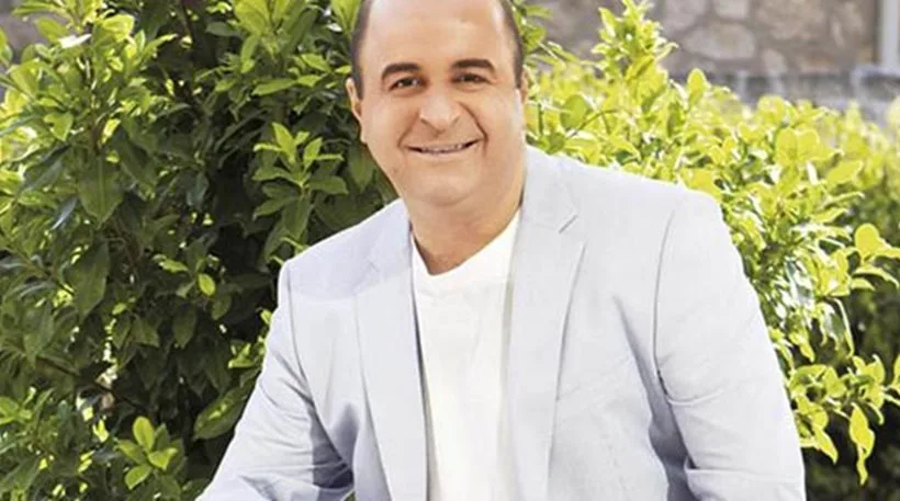 Ο Μάρκος Σεφερλής χαμογελαστός σε εξωτερικό χώρο με πράσινο φόντο.