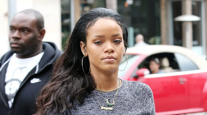 Κοντινό πλάνο της Rihanna με γκρι πλεκτή μπλούζα και μεγάλους κρίκους σκουλαρίκια.