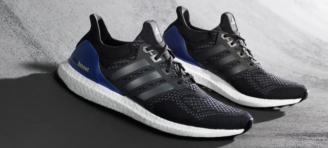 Ένα ζευγάρι αθλητικά παπούτσια adidas Ultra Boost σε μαύρο και μπλε χρώμα.