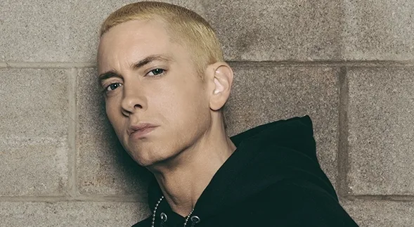 Ο Eminem με ξανθό μαλλί και μαύρο φούτερ μπροστά από τοίχο