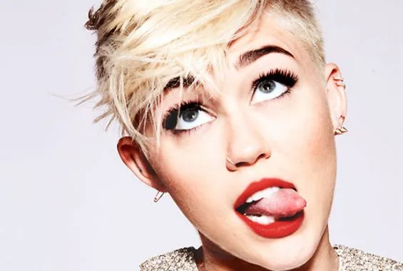Κοντινό πλάνο της Miley Cyrus με ξανθό κοντό μαλλί, βγάζοντας τη γλώσσα έξω.