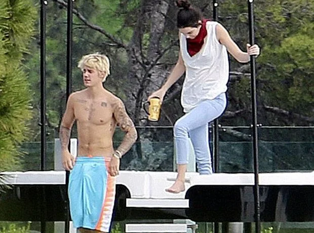 Ο Justin Bieber χωρίς μπλούζα δίπλα σε μια κοπέλα σε εξωτερικό χώρο.