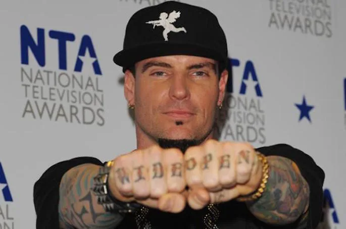 Ο Vanilla Ice ποζάρει δείχνοντας τα τατουάζ στα δάχτυλά του.