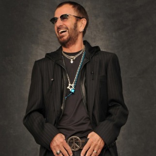Ο Ringo Starr με γυαλιά ηλίου, μαύρο σακάκι και ζώνη με το σήμα της ειρήνης.