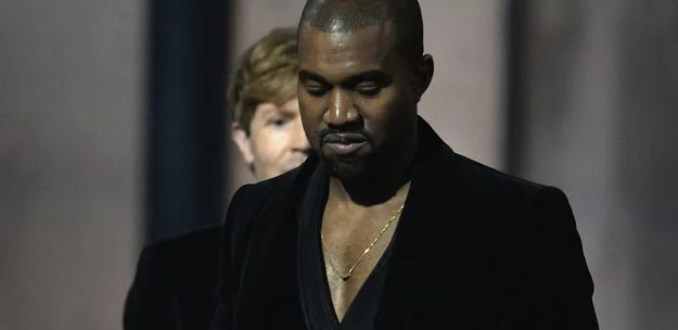 Ο Kanye West με μαύρο σακάκι και χρυσή αλυσίδα.