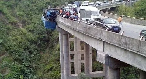 Ένα μπλε φορτηγό κρέμεται στην άκρη μιας γέφυρας μετά από ατύχημα.