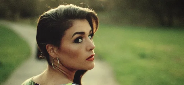 Η Jessie Ware κοιτάζει πάνω από τον ώμο της σε εξωτερικό χώρο.