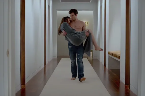 Ο Jamie Dornan μεταφέρει μια γυναίκα στην αγκαλιά του σε έναν διάδρομο.