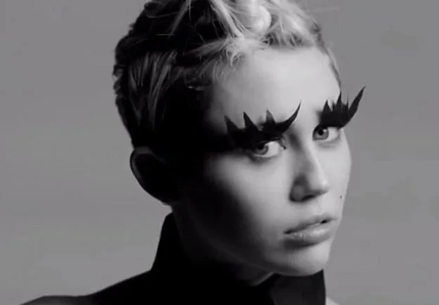 Η Miley Cyrus με εκκεντρικό μακιγιάζ ματιών σε ασπρόμαυρο πορτρέτο.