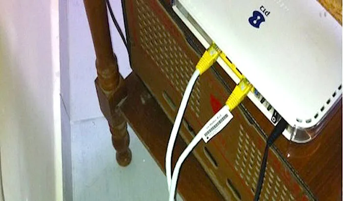 Ένα λευκό ρούτερ με δύο κίτρινα καλώδια Ethernet συνδεδεμένα.