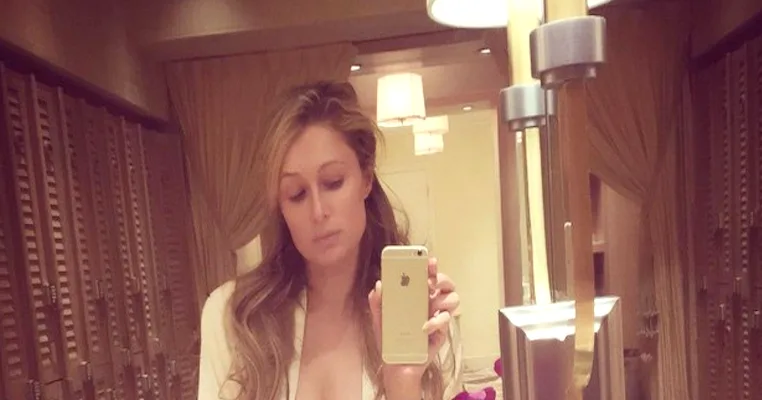 Η Paris Hilton βγάζει selfie με το κινητό της σε δωμάτιο με καθρέφτες.
