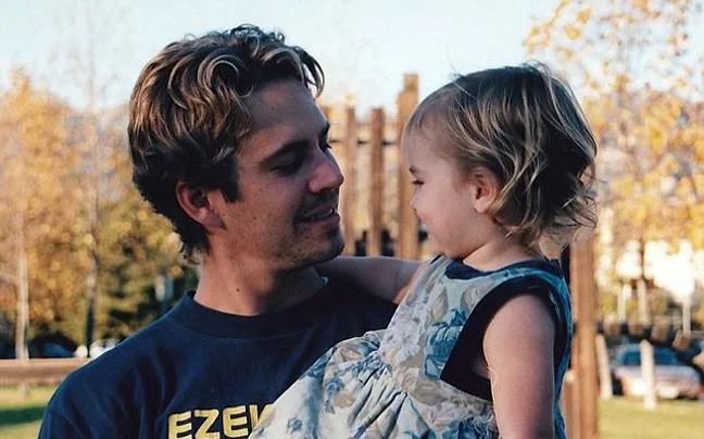 Ο Paul Walker κρατάει στην αγκαλιά του την κόρη του, Meadow, σε εξωτερικό χώρο.