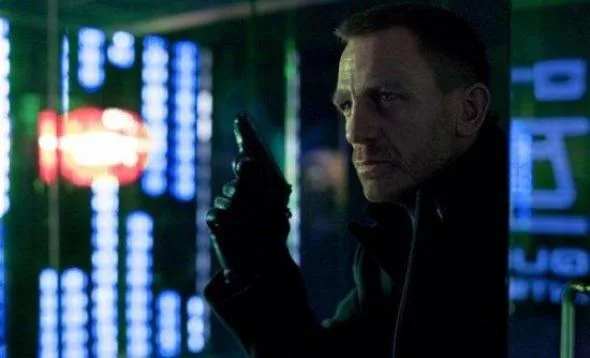 Ο James Bond κρατάει όπλο σε σκοτεινό περιβάλλον με μπλε φώτα.