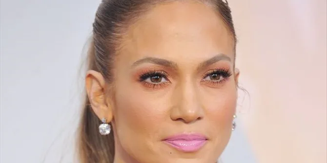 Κοντινό πορτρέτο της Jennifer Lopez με πιασμένα μαλλιά και ροζ κραγιόν.