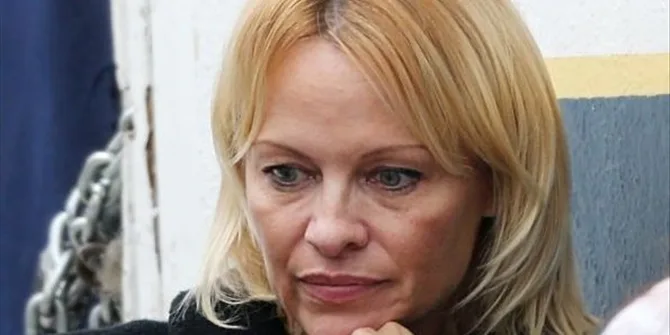 Κοντινό πλάνο της Pamela Anderson με ξανθά μαλλιά και σκεπτικό ύφος.