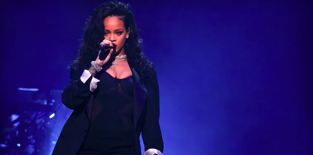 Η Rihanna τραγουδάει στη σκηνή κρατώντας μικρόφωνο.