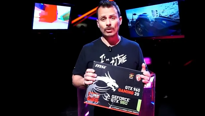 Παρουσιαστής του Mad Games and Gadgets κρατάει το κουτί μιας κάρτας γραφικών MSI GeForce GTX 960.