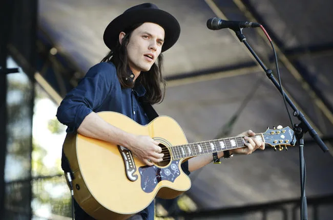 Ο James Bay παίζει ακουστική κιθάρα και τραγουδάει σε σκηνή.