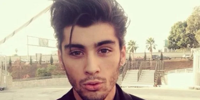 Ο Zayn Malik σε κοντινό πλάνο με φόντο εξωτερικό χώρο.