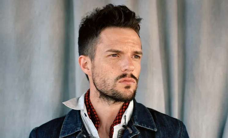 Ο Brandon Flowers με τζιν τζάκετ και μαντήλι στον λαιμό.