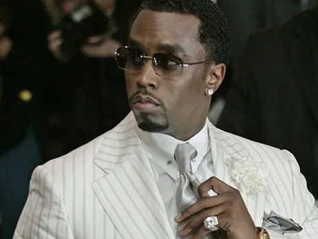 Ο ράπερ Diddy με λευκό ριγέ κοστούμι, γυαλιά ηλίου και κοσμήματα.
