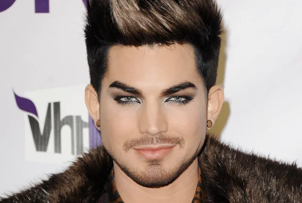 Ο Adam Lambert με έντονο μακιγιάζ ματιών και γούνινο παλτό.