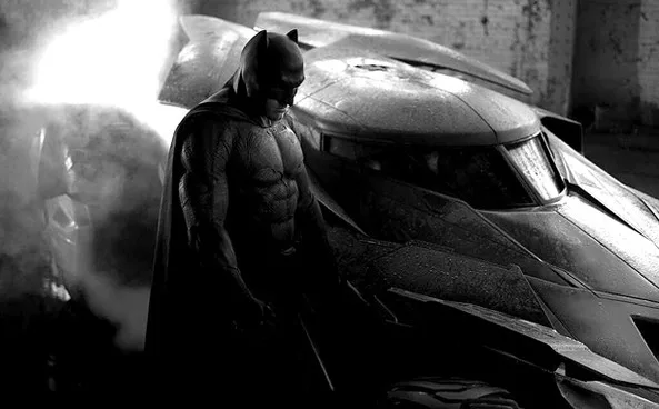 Ο Batman δίπλα στο Batmobile σε ασπρόμαυρο φόντο.
