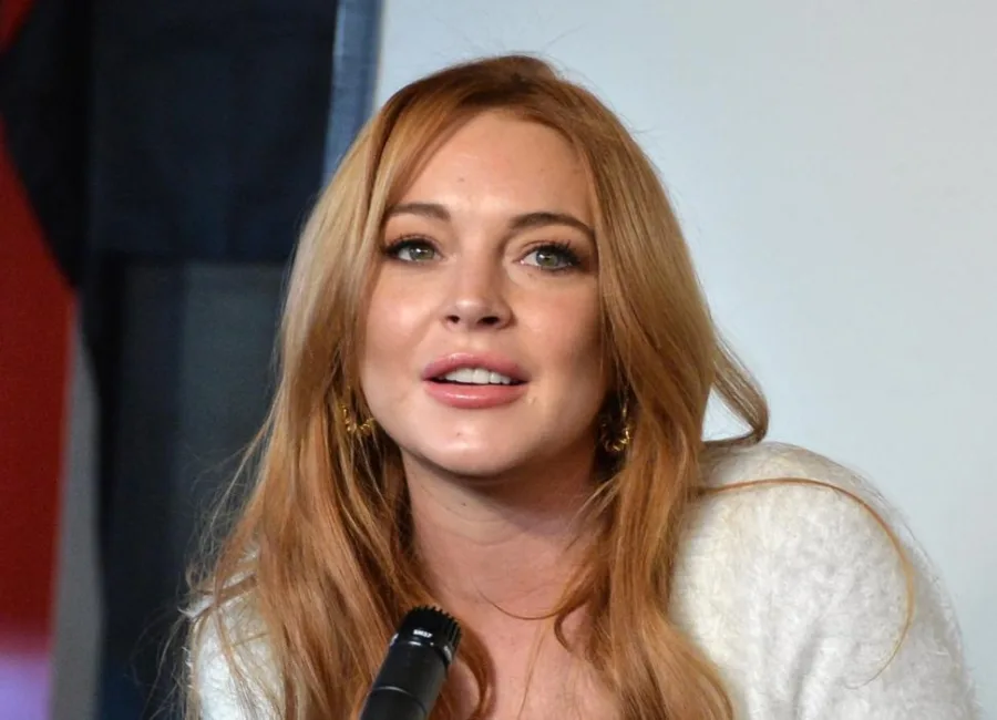 Η Lindsay Lohan σε κοντινό πλάνο με κόκκινα μαλλιά και λευκό πουλόβερ.