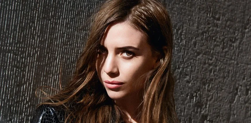 Η Lykke Li ποζάρει μπροστά από έναν σκούρο τοίχο.