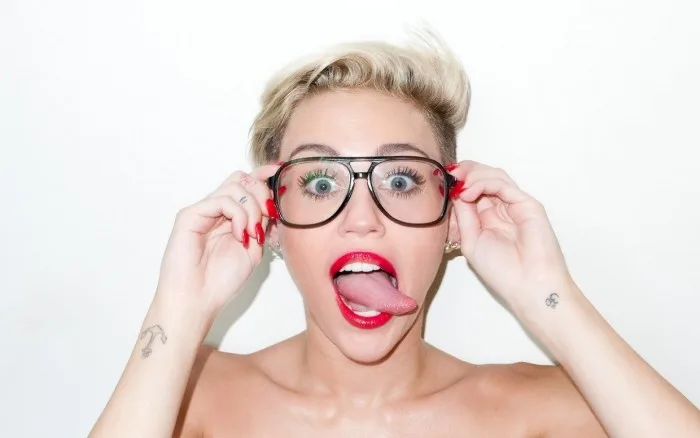 Η Miley Cyrus με γυαλιά ηλίου και βγαλμένη γλώσσα.