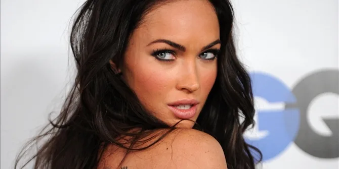 Η Megan Fox κοιτάζει πάνω από τον ώμο της σε εκδήλωση.