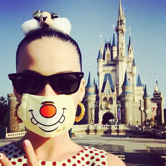 Η Katy Perry με μάσκα και γυαλιά ηλίου μπροστά από το κάστρο της Disneyland.